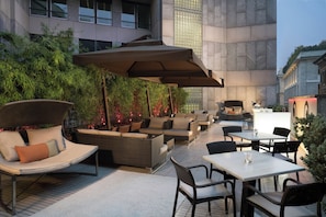 Een terras buiten met zitplaatsen, tafels en parasols.