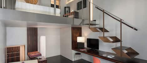 Um interior moderno com uma escada, um sofá, uma mesa de centro e uma televisão.