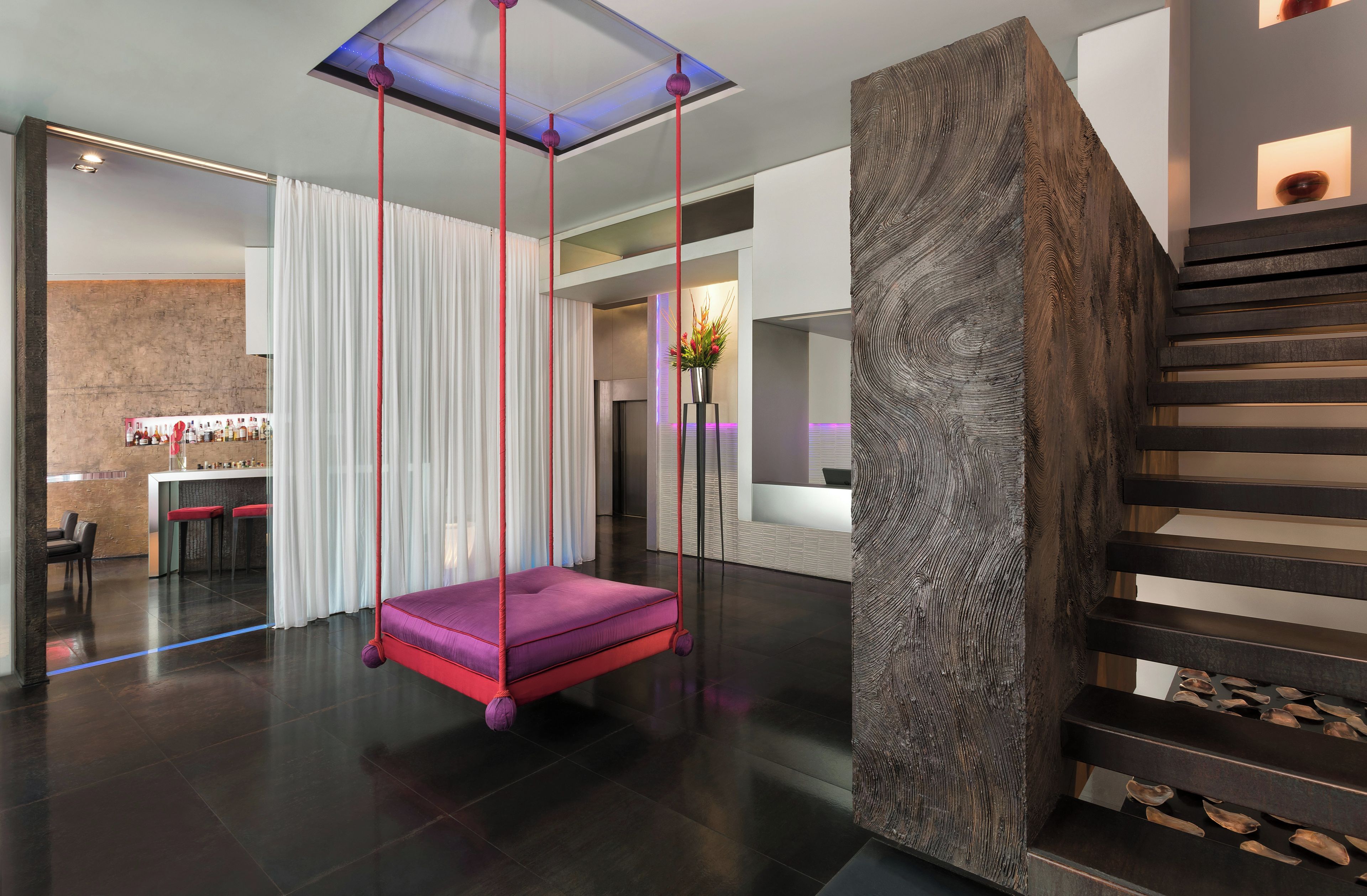 Un interior moderno con una silla colgante, una escalera y una zona de bar.