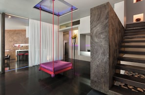 A modern interior with a hanging chair, a staircase, and a bar area. - Sina The Gray (Milan)