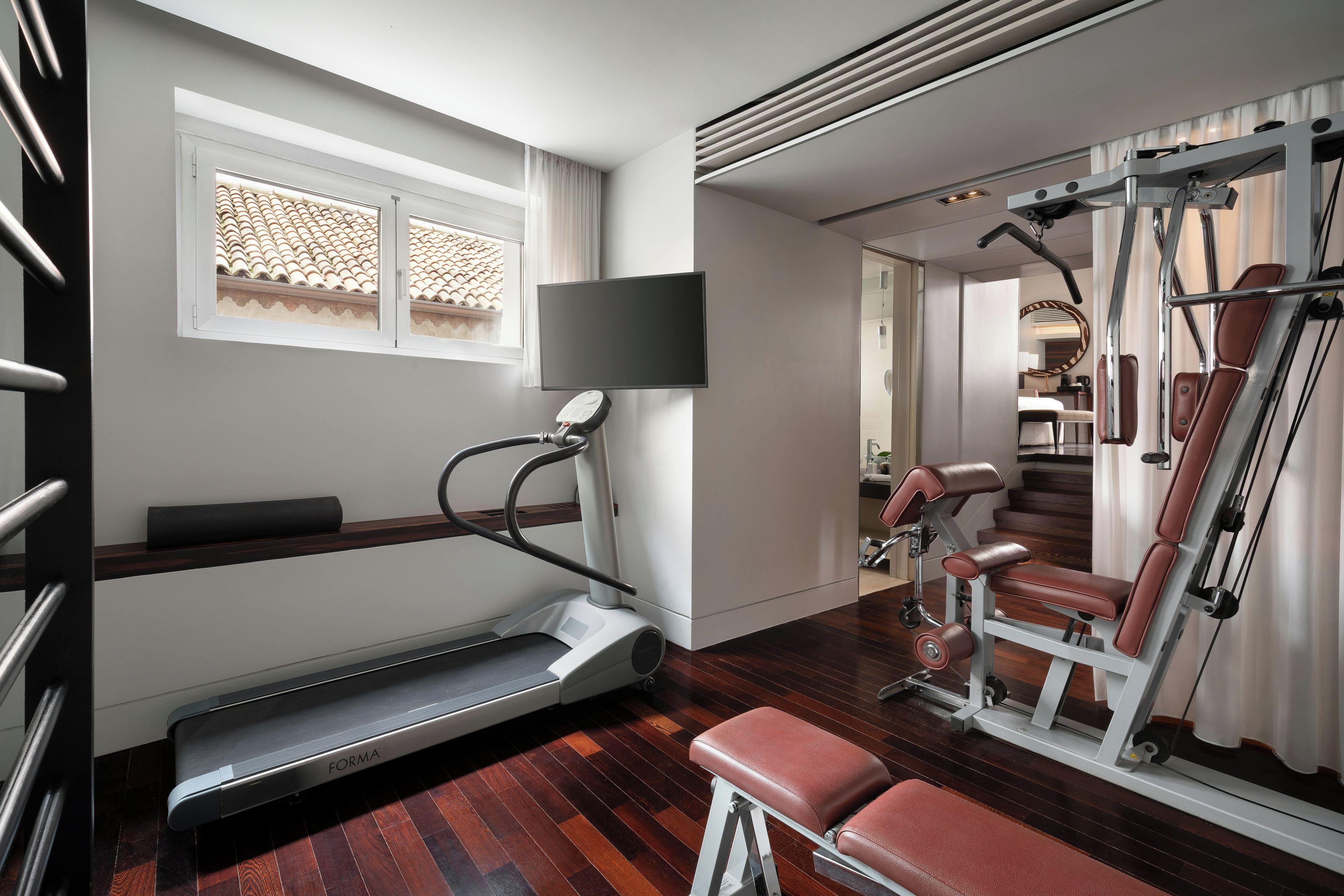 Ein modernes Fitnessstudio mit Laufband, Langhantelbank und Trainingsgeräten.