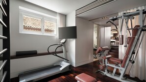 A modern gym with a treadmill, weight bench, and exercise equipment. - Sina The Gray (Milan)