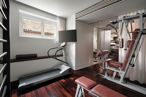 A modern gym with a treadmill, weight bench, and exercise equipment. - Sina The Gray (Milan)