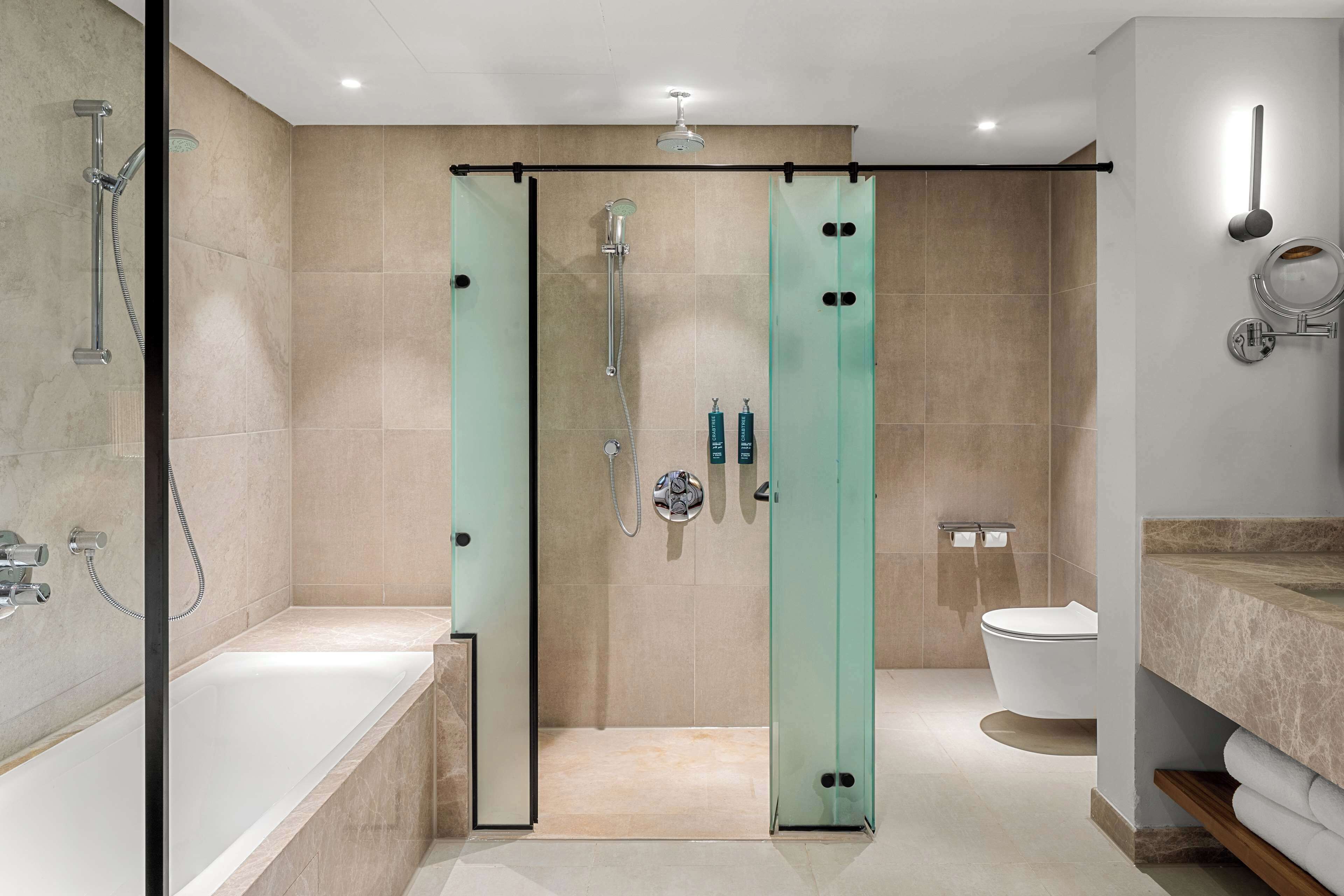 A modern bathroom with a glass-enclosed shower, a bathtub, and a toilet.
