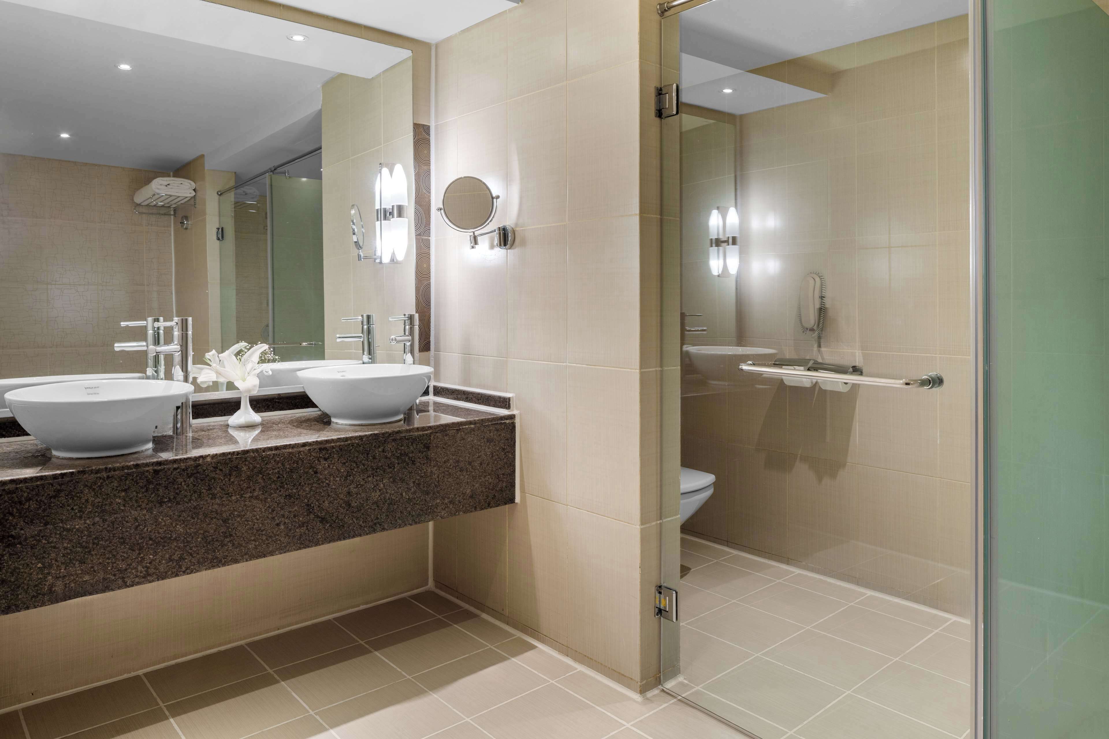 A modern bathroom with two sinks, a shower, and a glass-enclosed shower area.