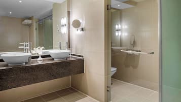 A modern bathroom with two sinks, a shower, and a glass-enclosed shower area.