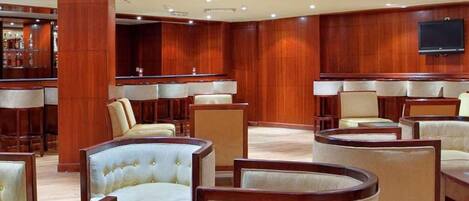 A spacious lobby with multiple seating areas, a bar, and a flat-screen TV mounted on the wall.