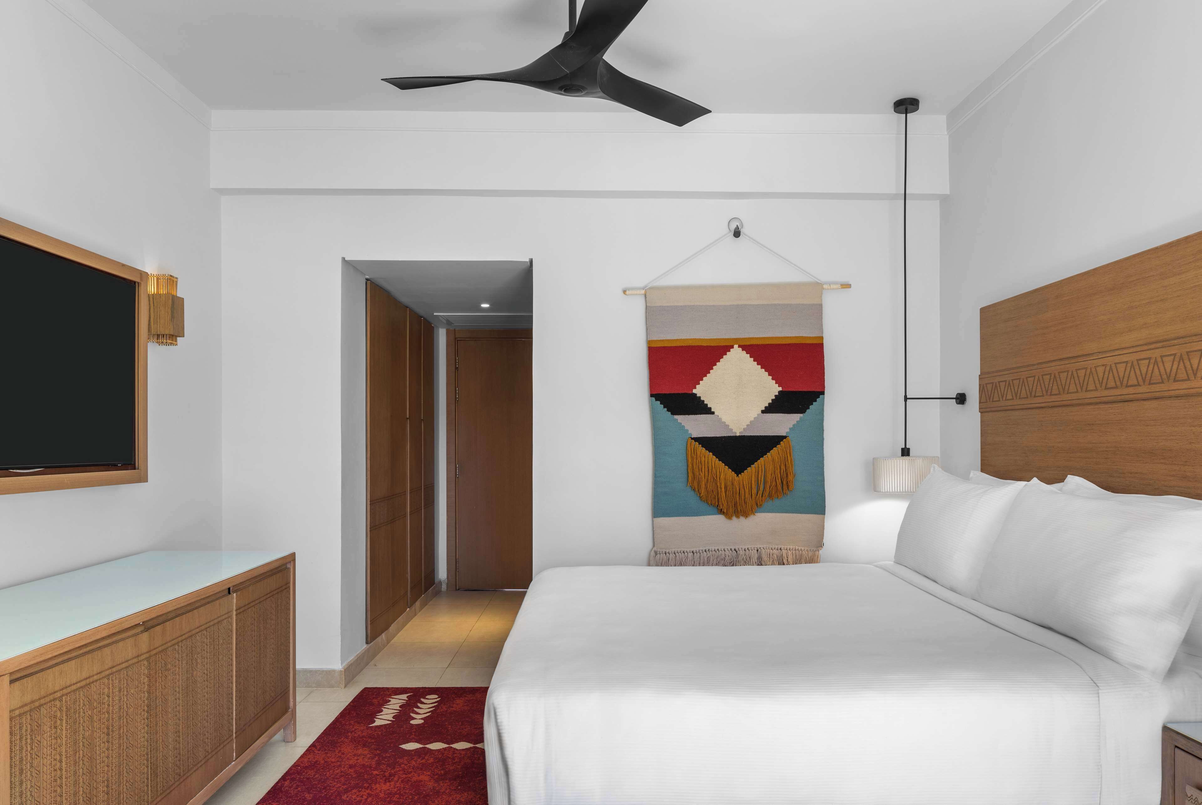 Une chambre à coucher comprenant un lit, un bureau, une tapisserie murale et un ventilateur de plafond.