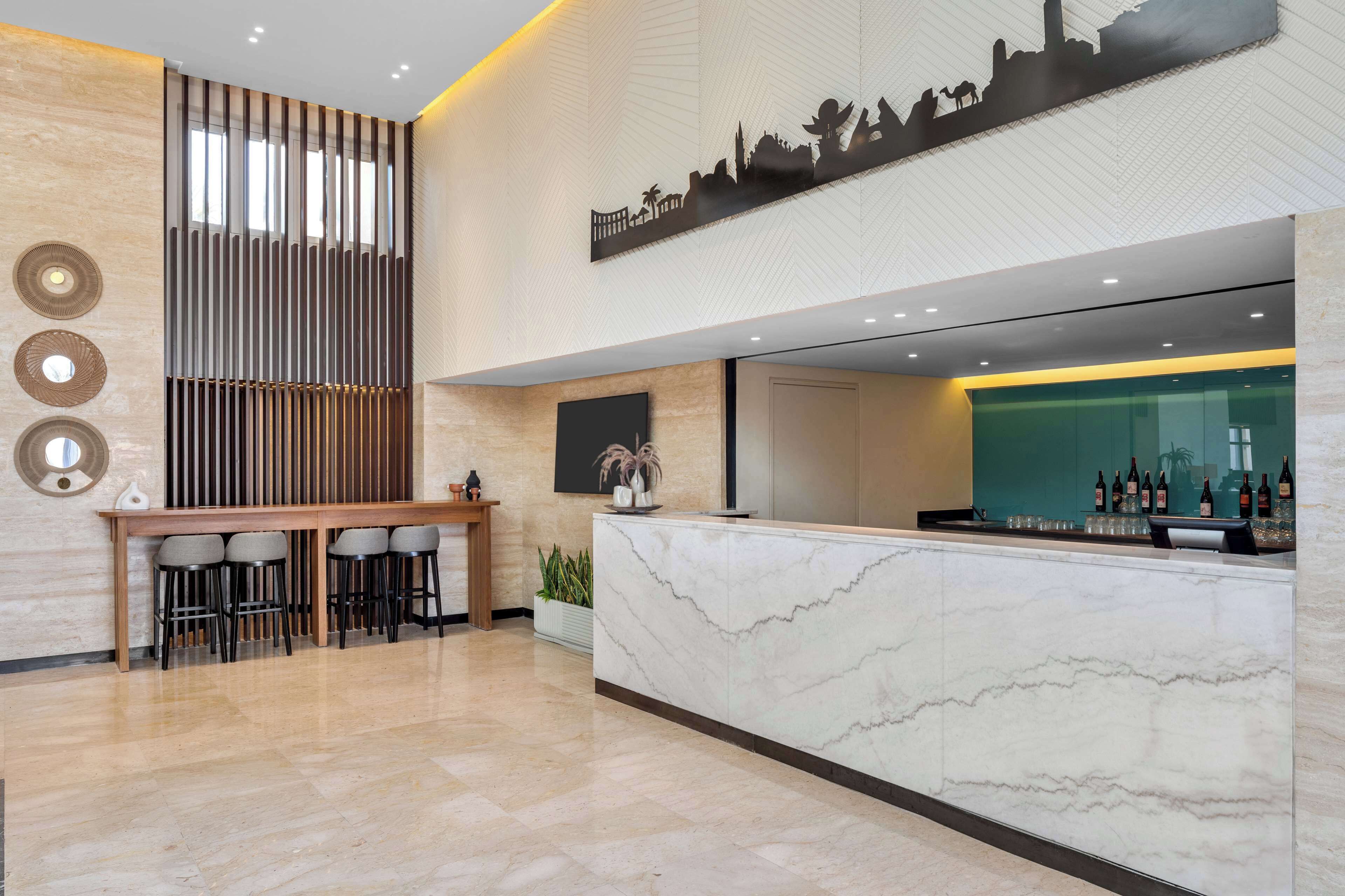 A modern reception area with a marble counter, bar stools, and a cityscape artwork.