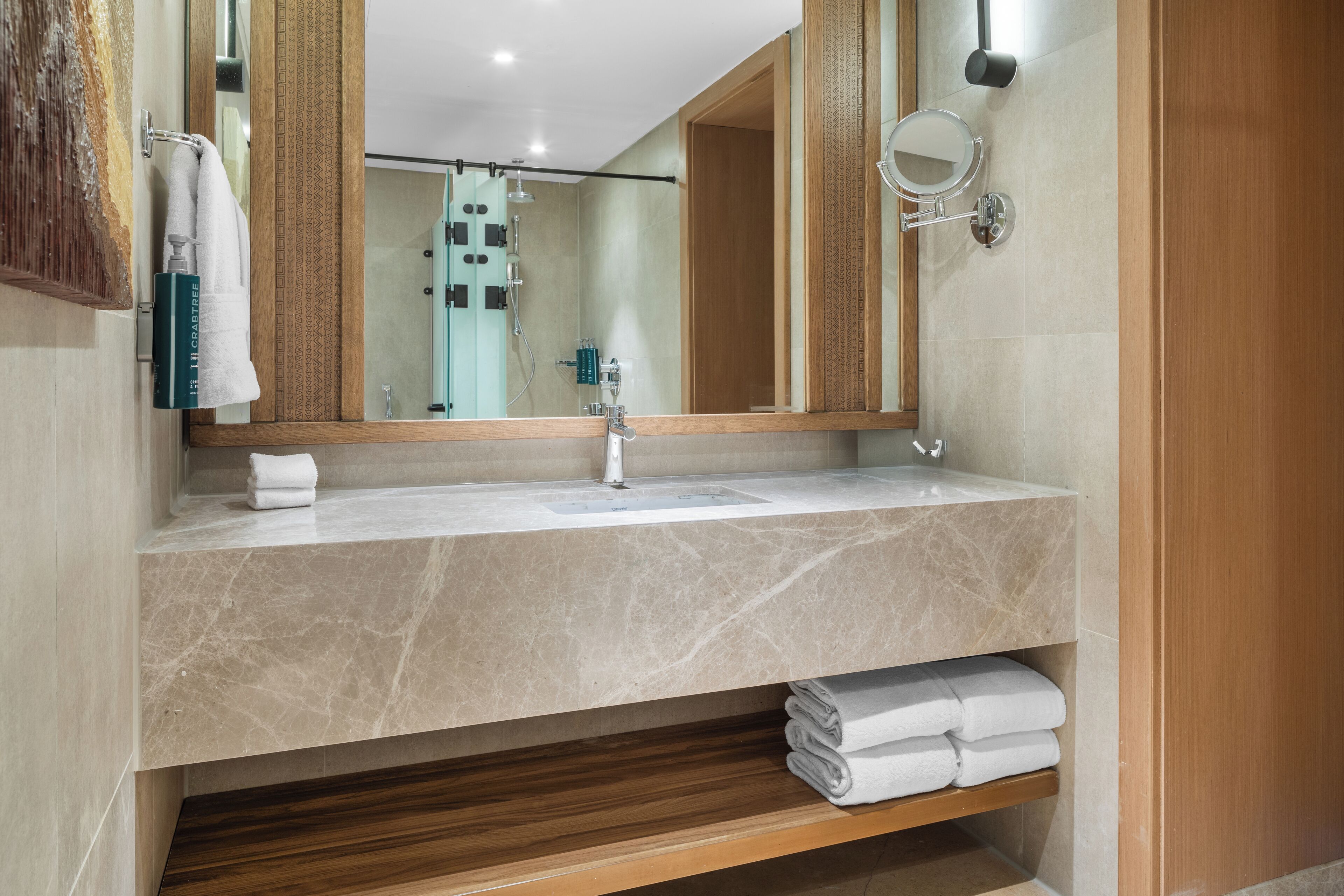 Une salle de bain moderne avec un lavabo en marbre, un grand miroir et un meuble-lavabo en bois.