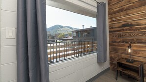 A room with a large window, wooden panel wall, and a small table with a lamp. - Bel Aire Motel (Missoula)