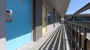 A corridor with a blue door labeled 204, a yellow door, and a metal railing. - Bel Aire Motel (Missoula)