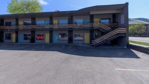 A multi-story motel with a central staircase, a parking lot, and a clear sky. - Bel Aire Motel (Missoula)