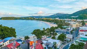 Eine Küstenstadt mit Strand, Gebäuden und Bergen im Hintergrund.