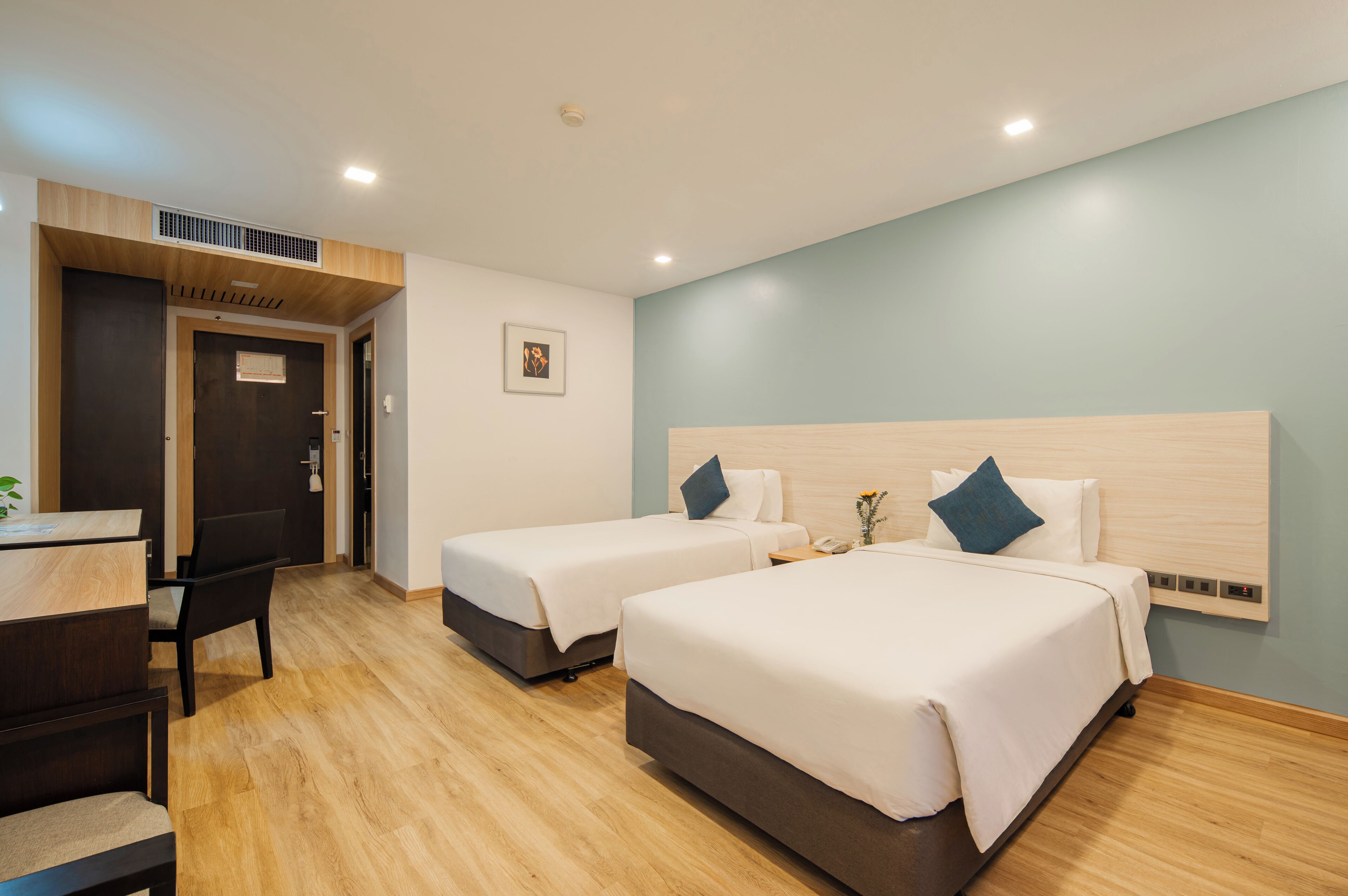 A hotel room with two beds, a desk, and a chair.