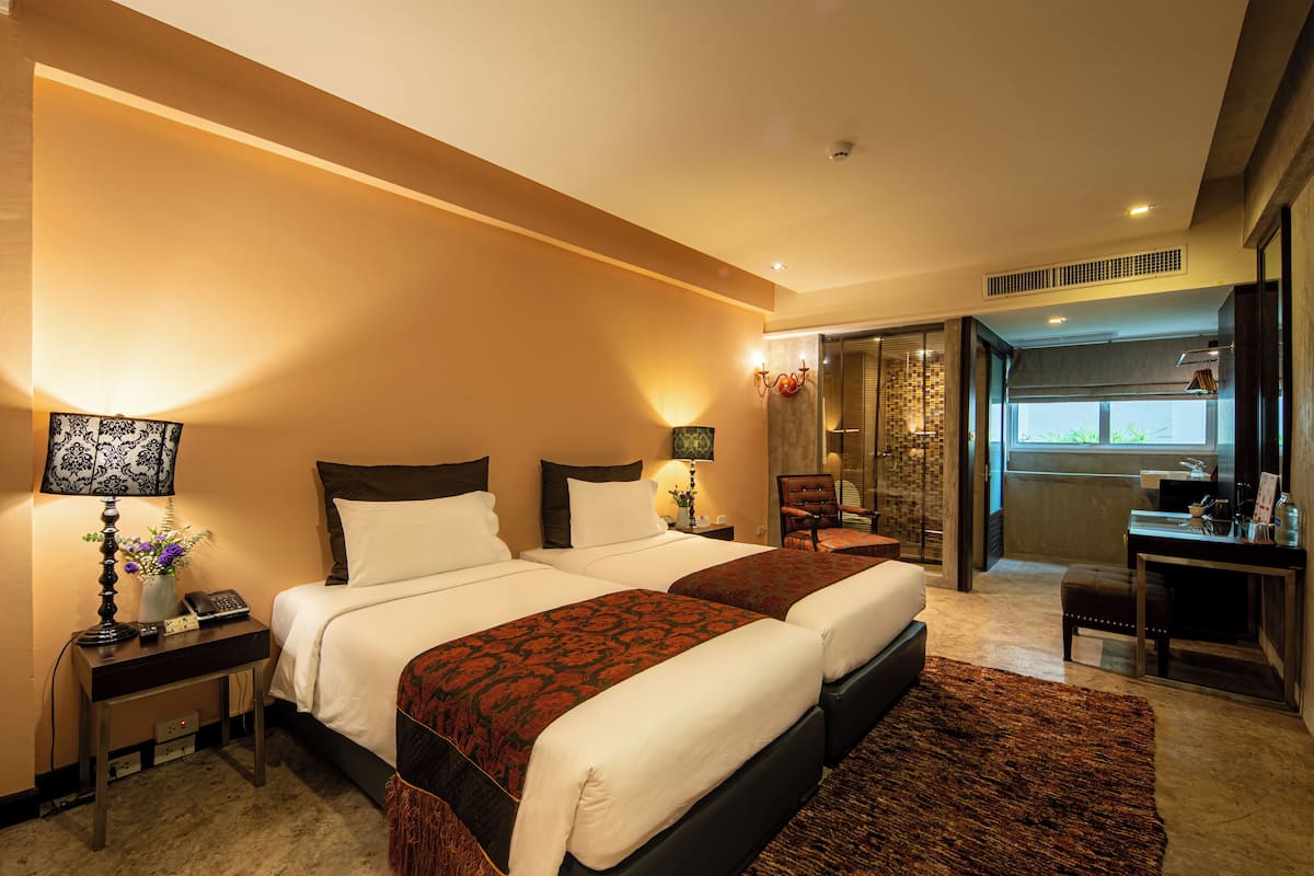 A hotel room with a large bed, bedside tables, a desk, and a bathroom visible through an open door.