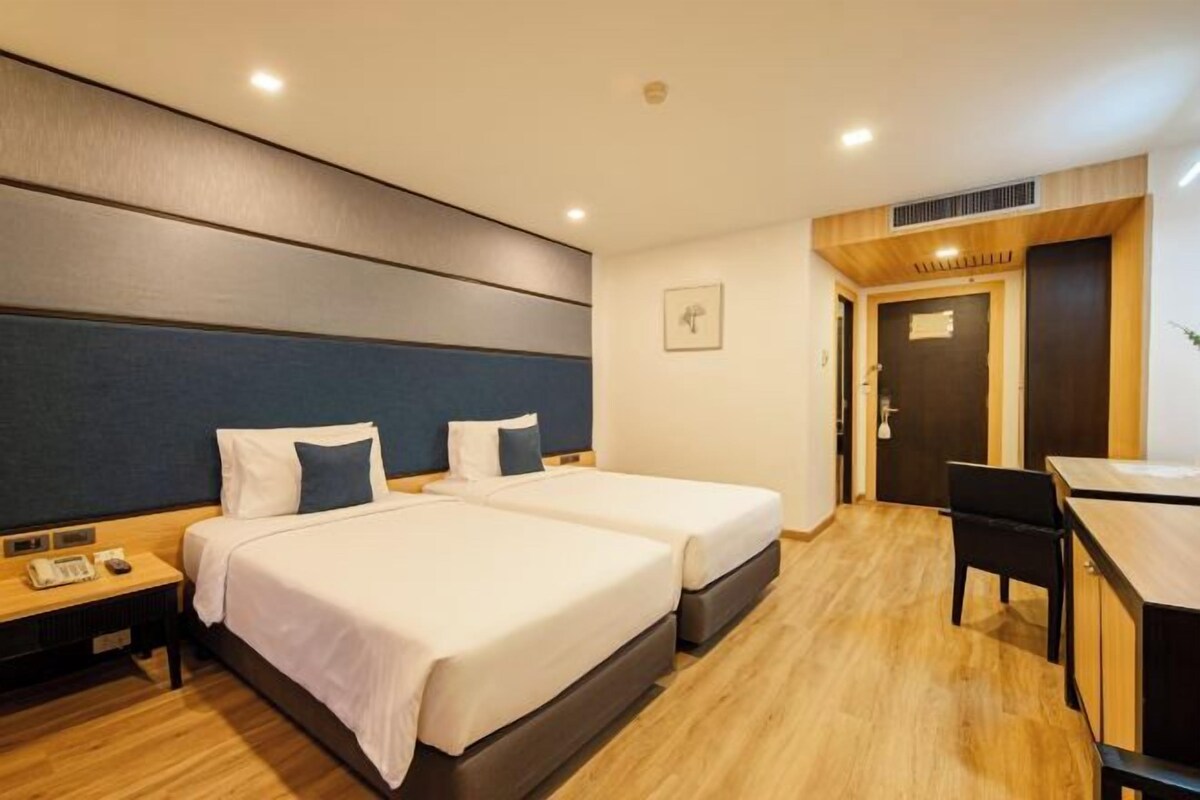 A hotel room with two beds, a desk, and a chair.