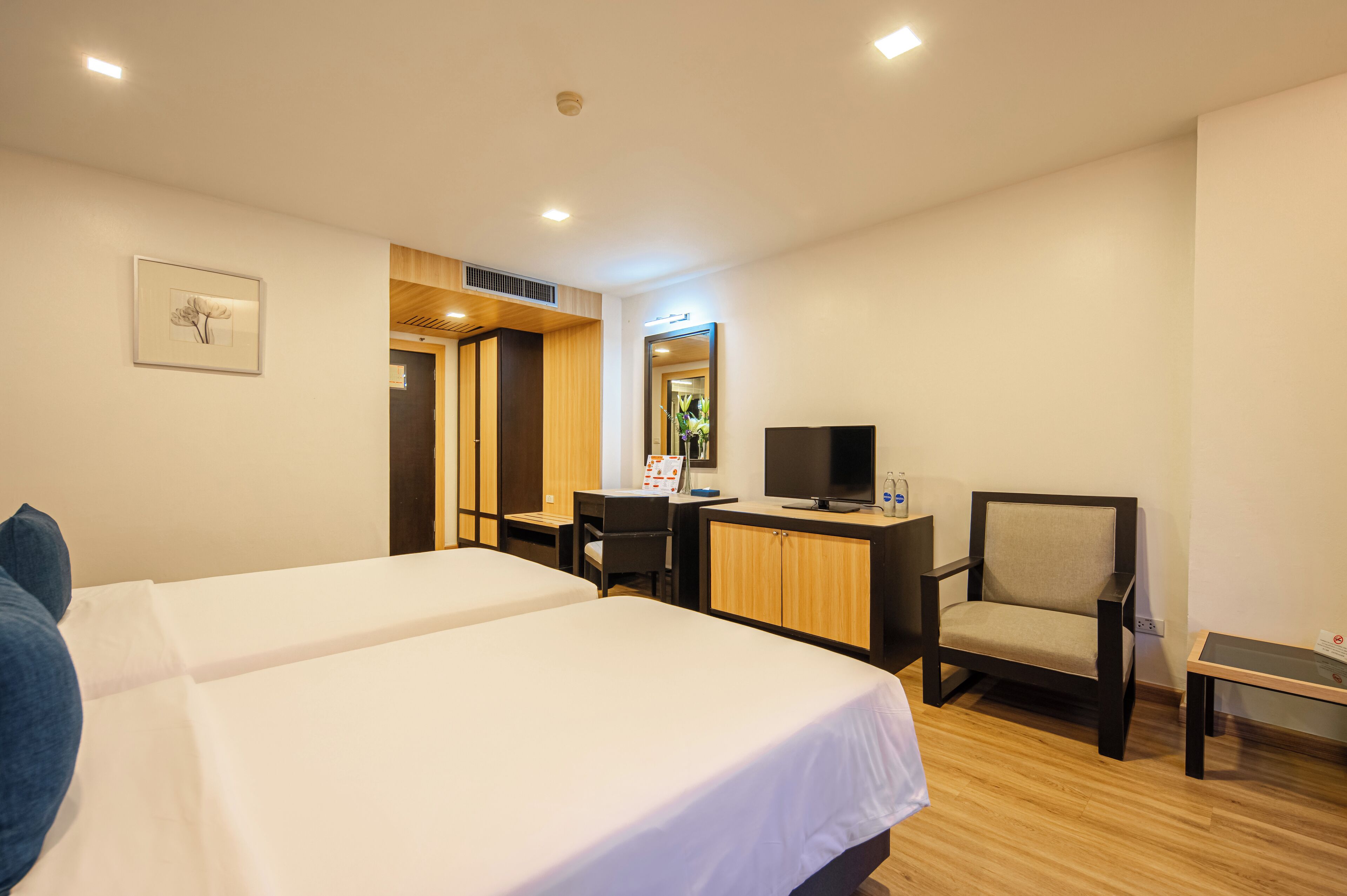 A hotel room with two beds, a desk with a chair, a television, and a small table.
