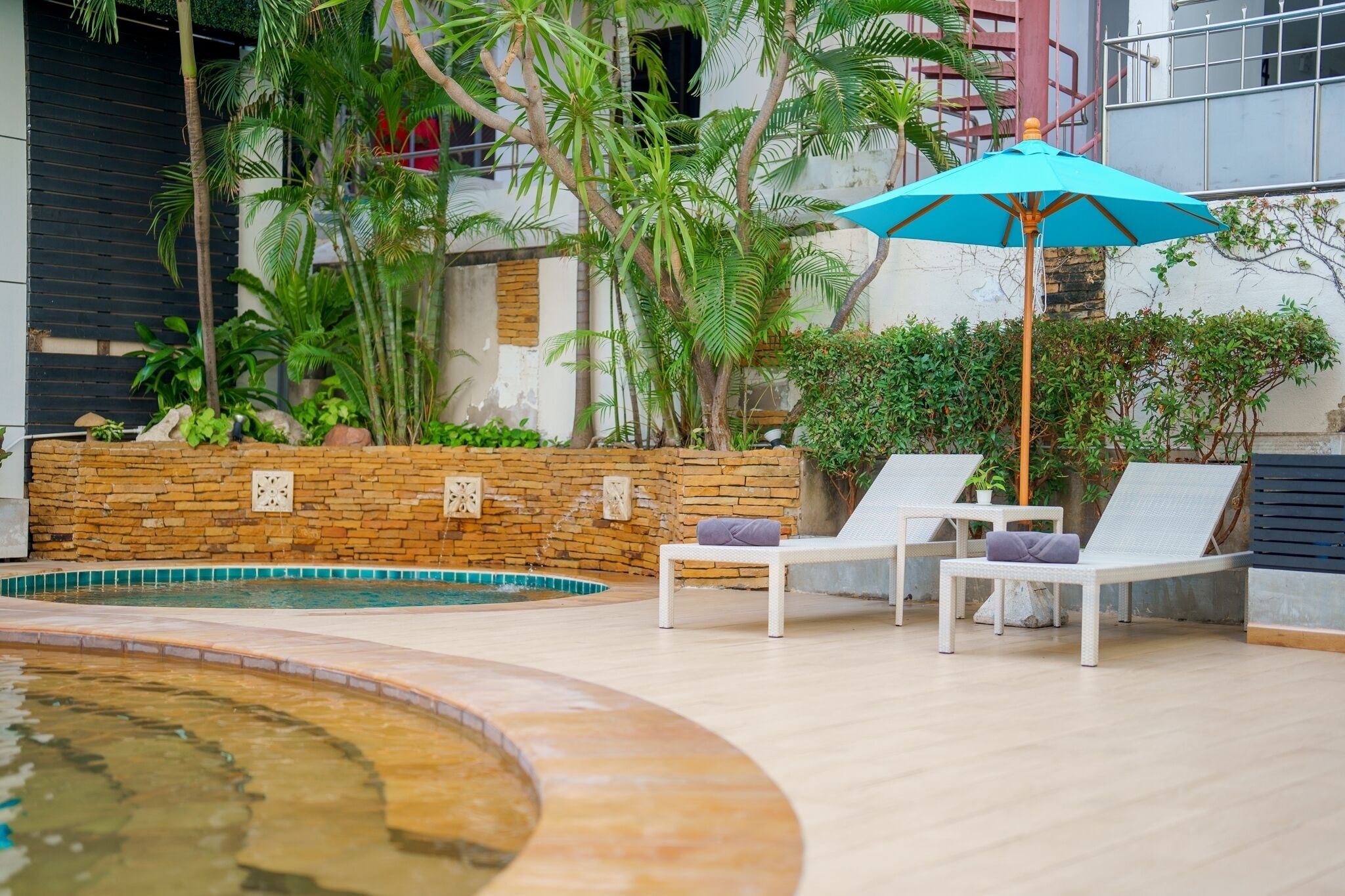 Un espace aménagé au bord de la piscine, avec des chaises longues et un parasol bleu.