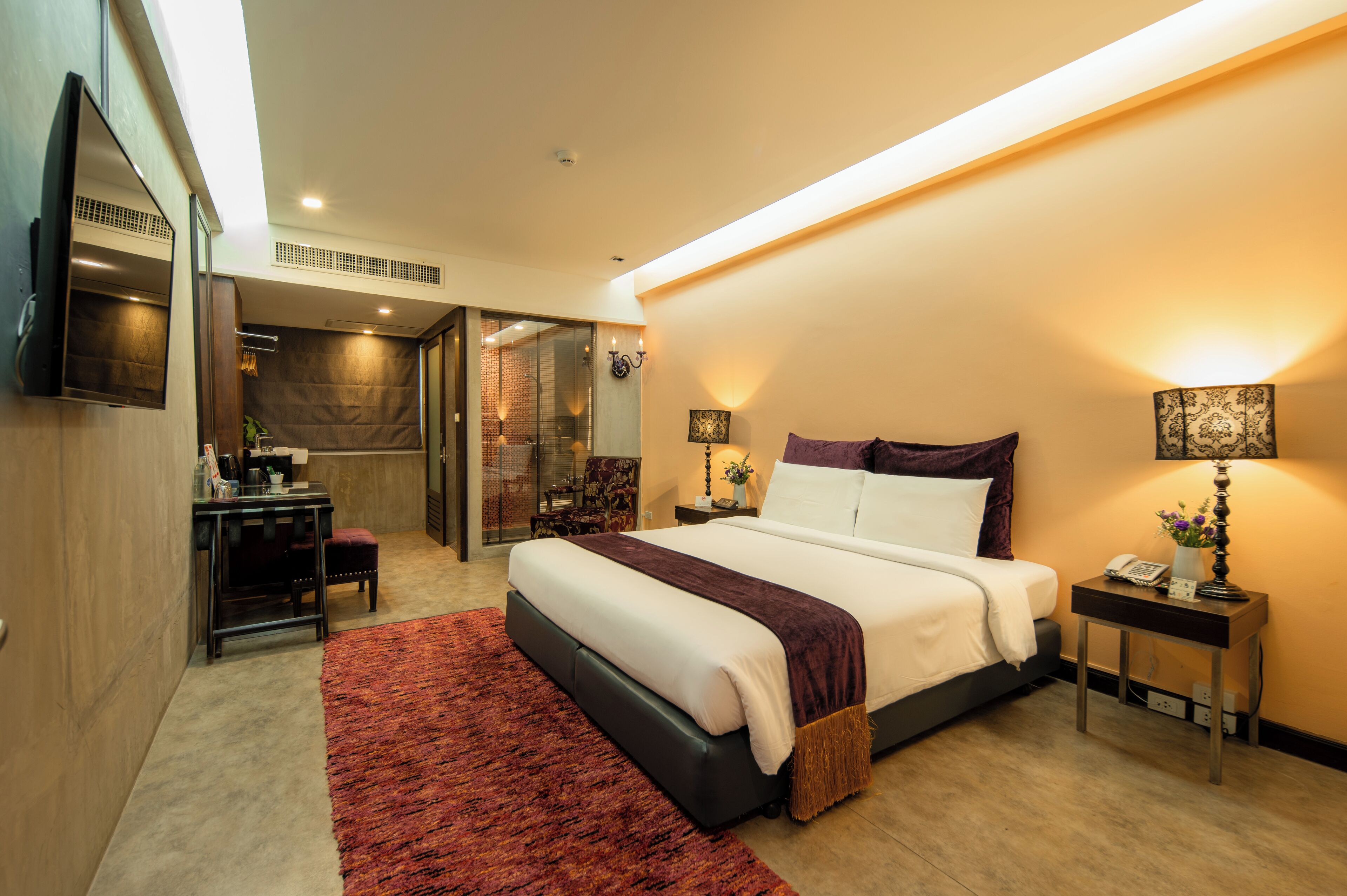 A modern hotel room with a large bed, a desk, and a shower area.