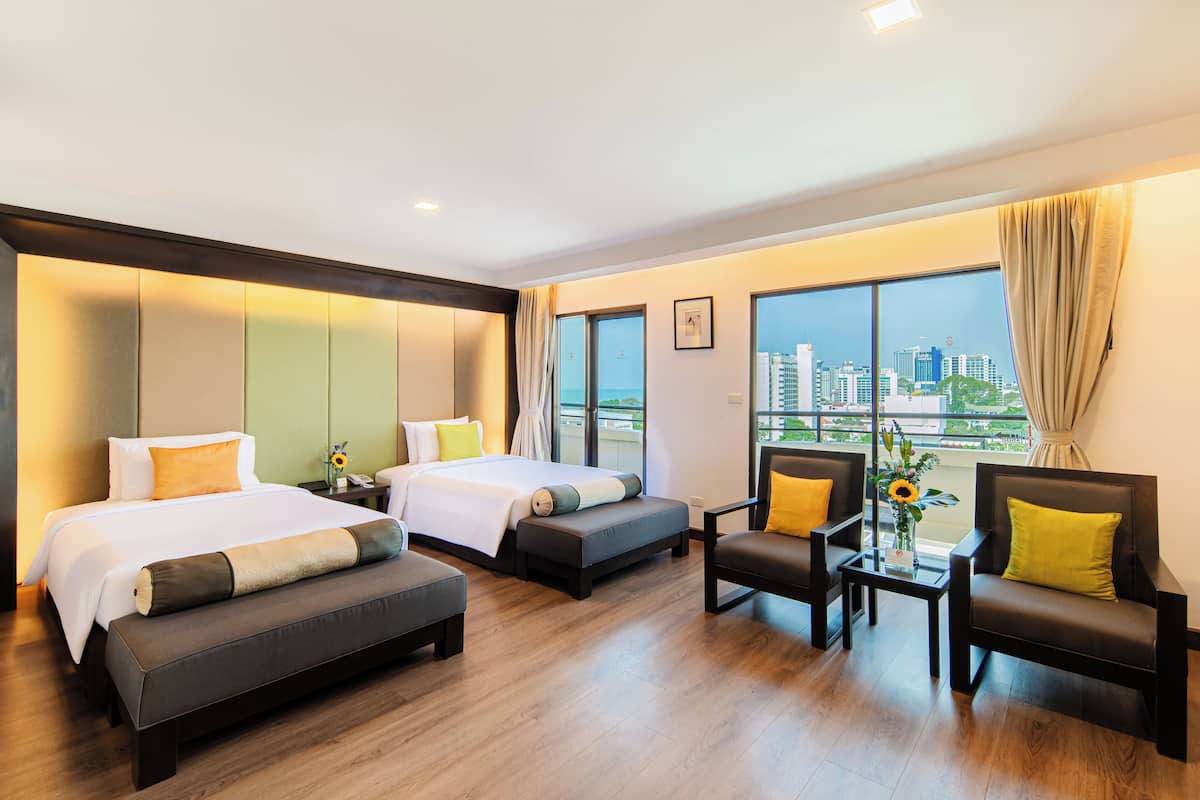A hotel room with two beds, a sofa, a chair, and a small table.
