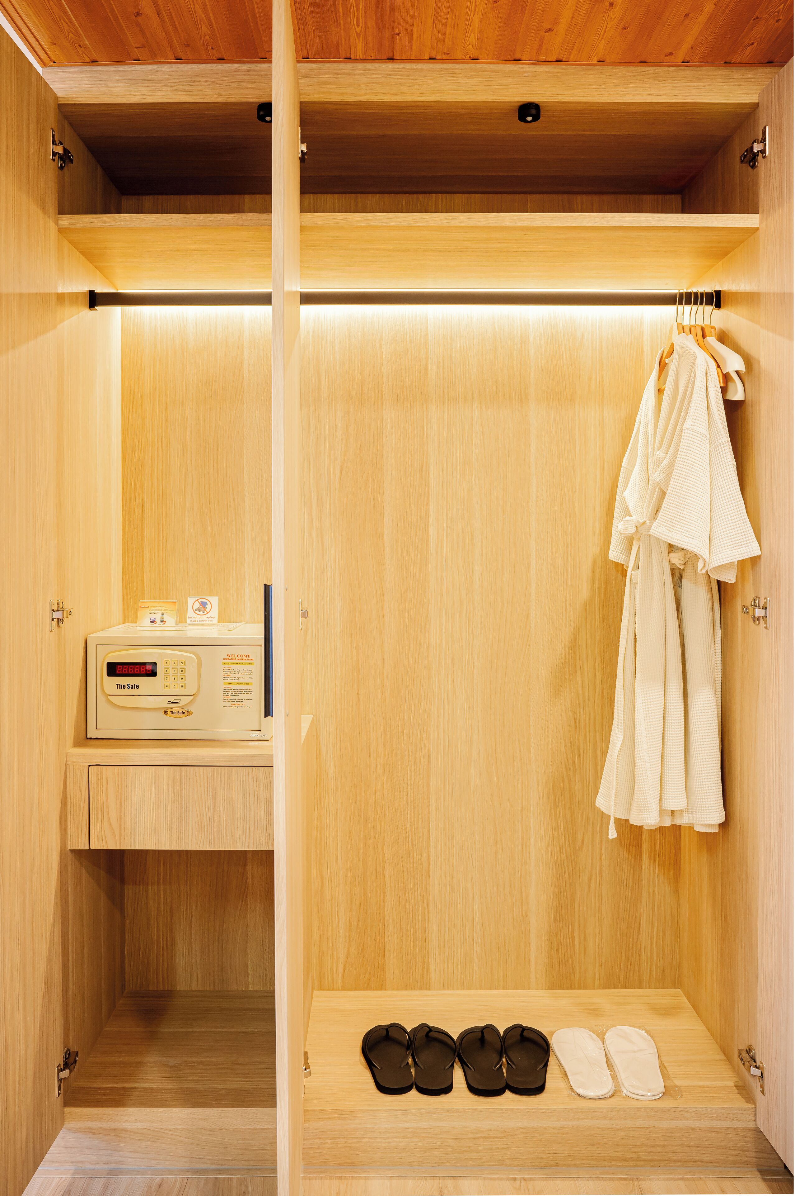 Een houten sauna met bedieningspaneel, handdoeken en slippers.