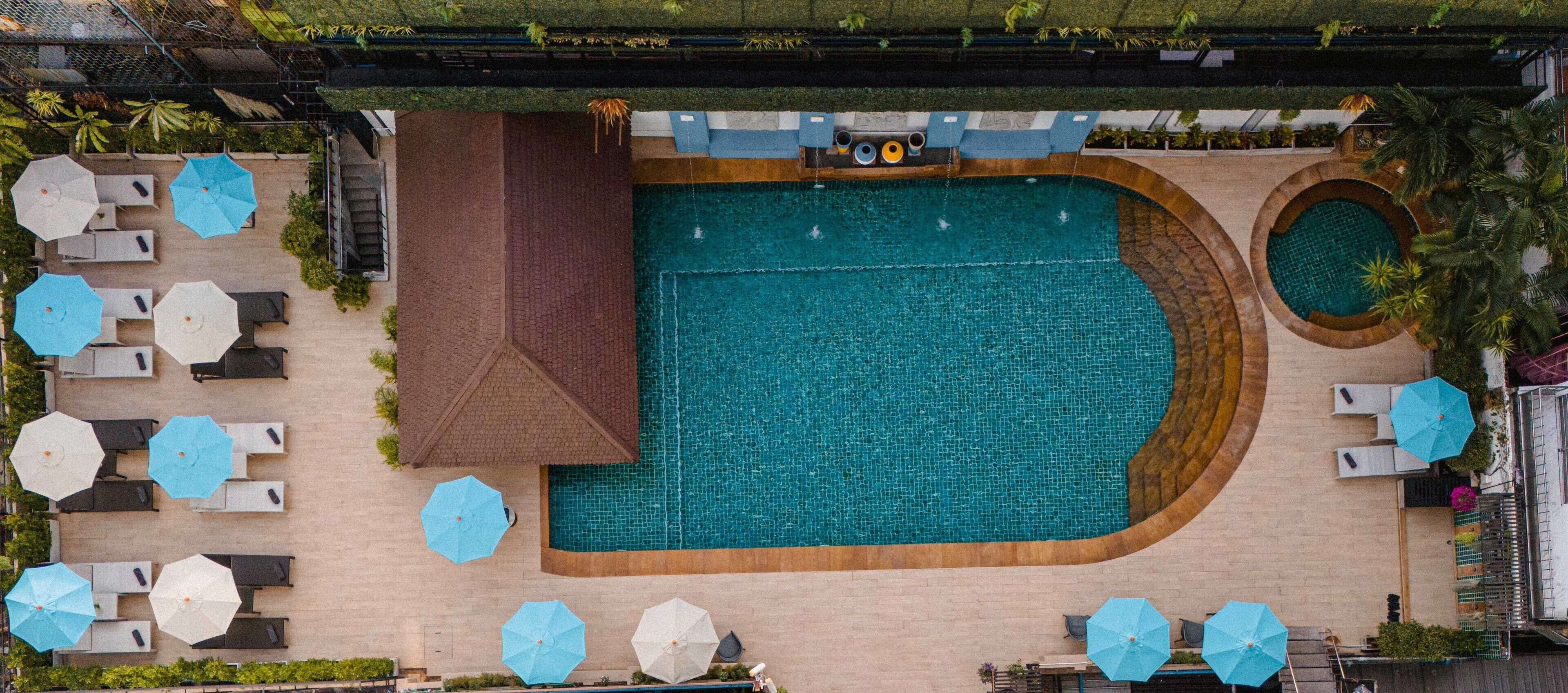 An aerial view of a hotel pool area with multiple seating arrangements and a large central pool.