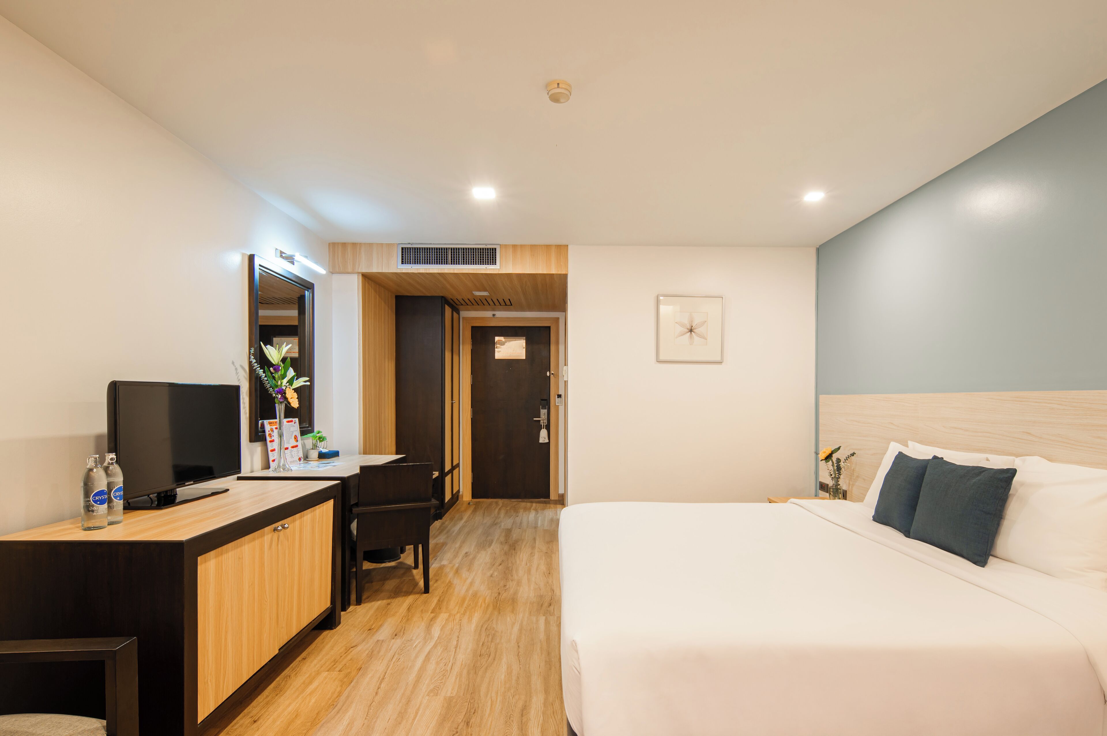 Une chambre d’hôtel comprenant un lit, un bureau avec un ordinateur, une télévision et un petit coin salon.