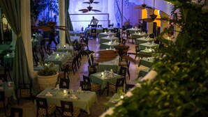 Un restaurante con varias mesas dispuestas para comer, que cuenta con un ventilador de techo e iluminación ambiental.