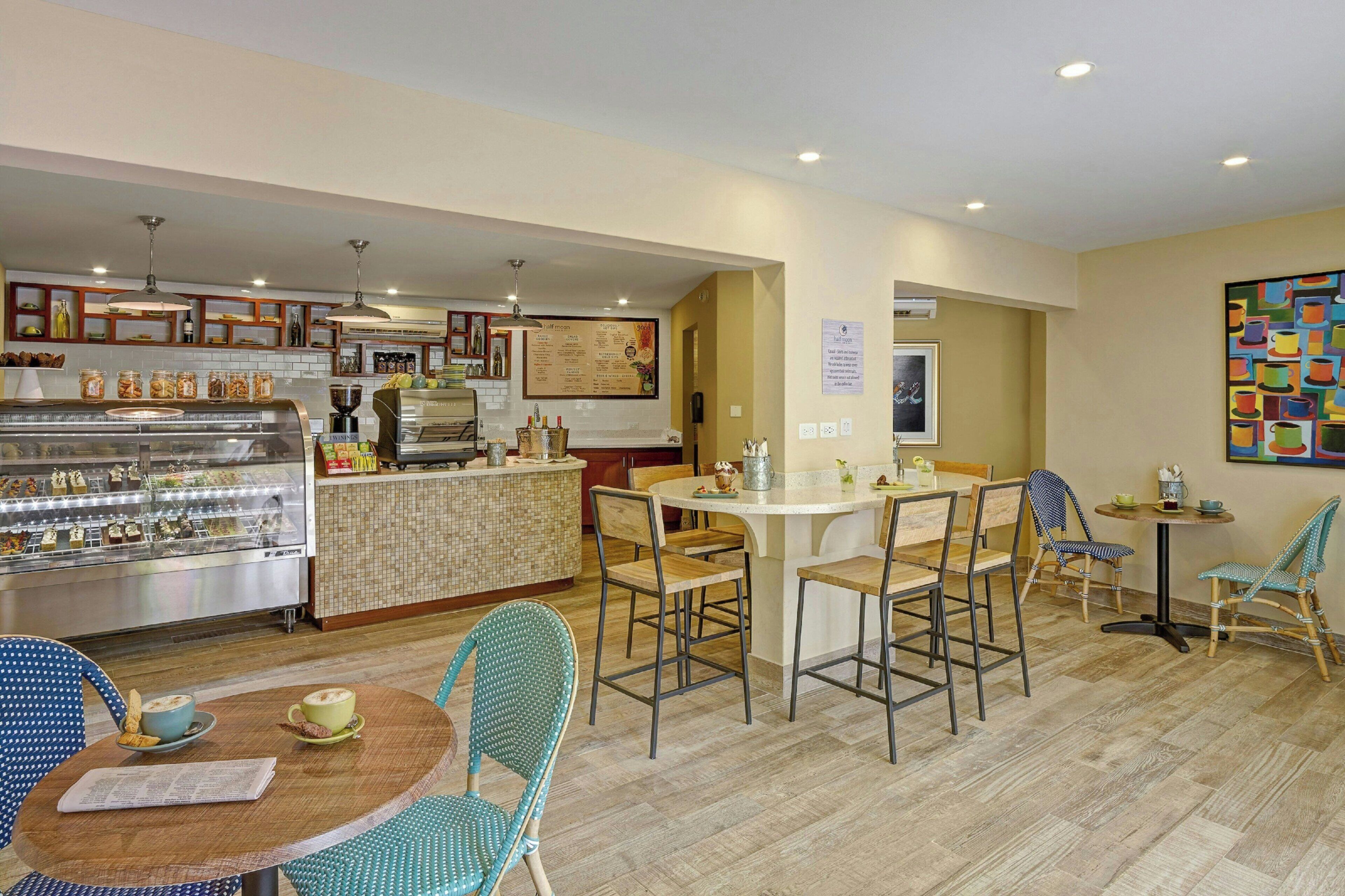 A restaurant with a counter, chairs, tables, and a menu board.