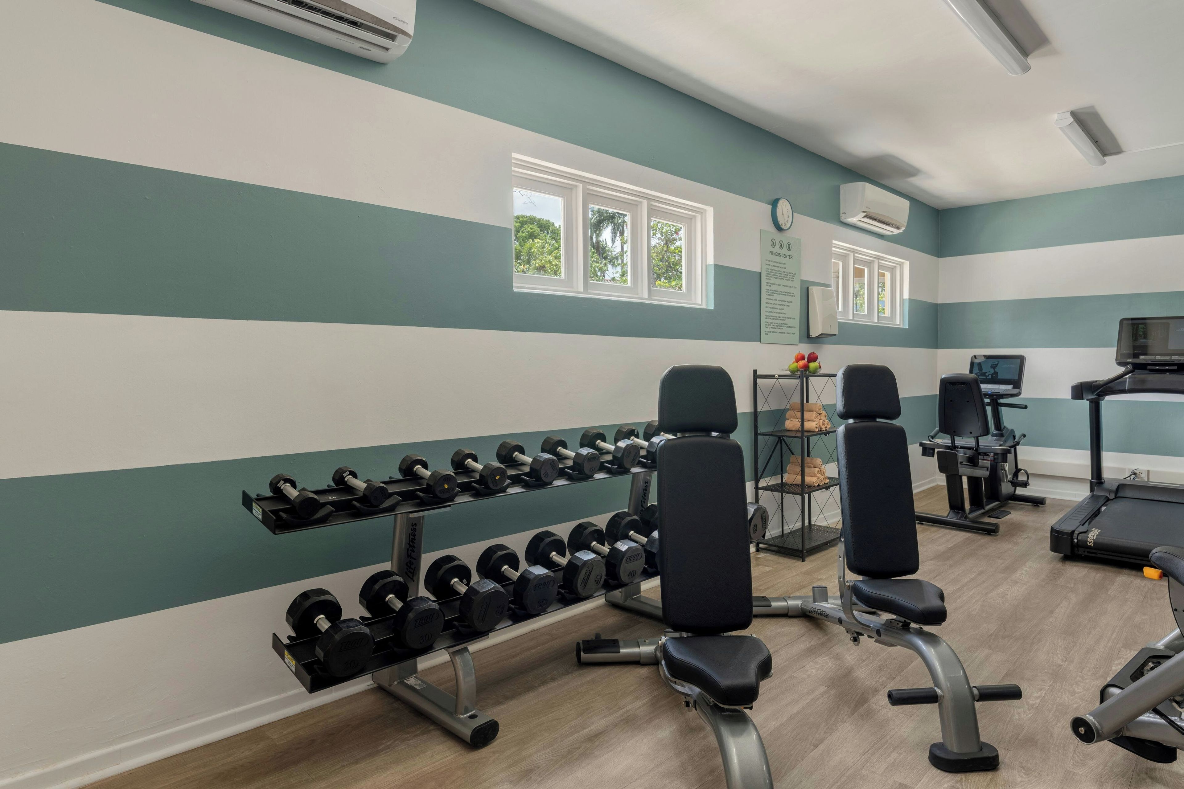 Un gimnasio con equipo de levantamiento de pesas, máquinas de ejercicio y una cinta de correr.
