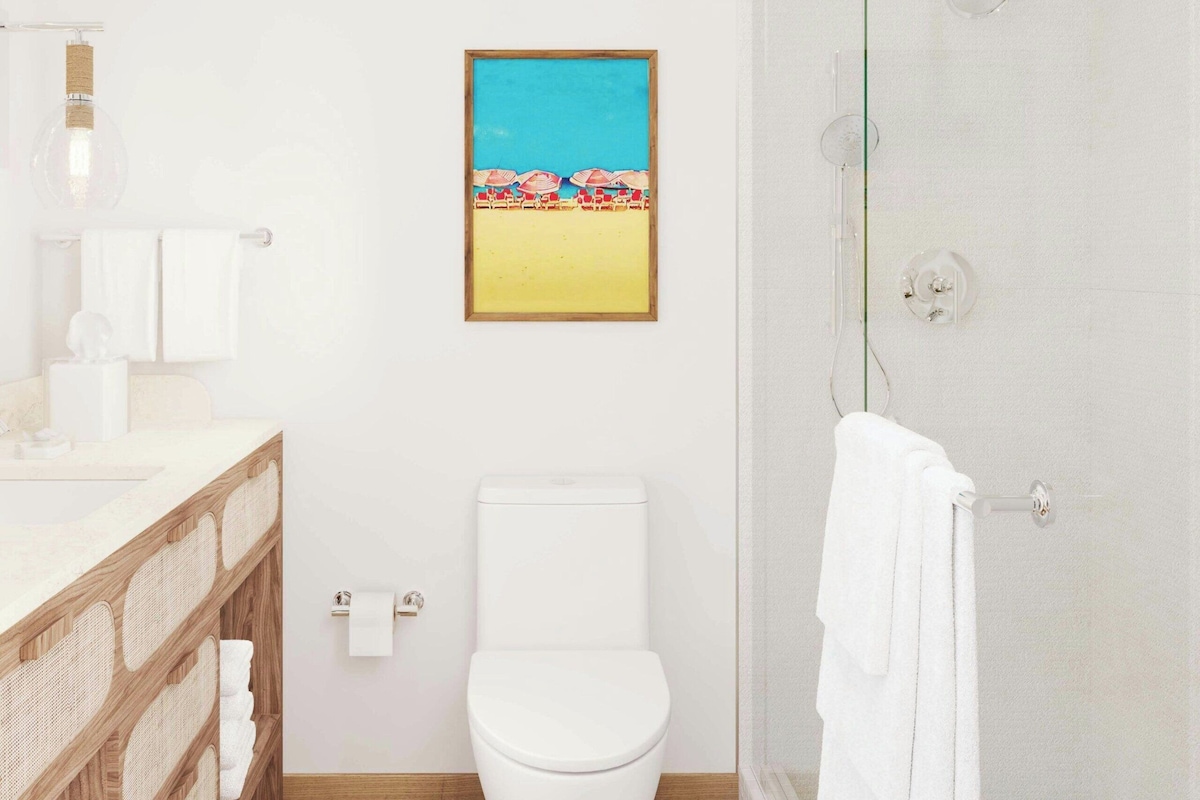 Un baño con inodoro, ducha, lavamanos y un estante de madera con toallas.