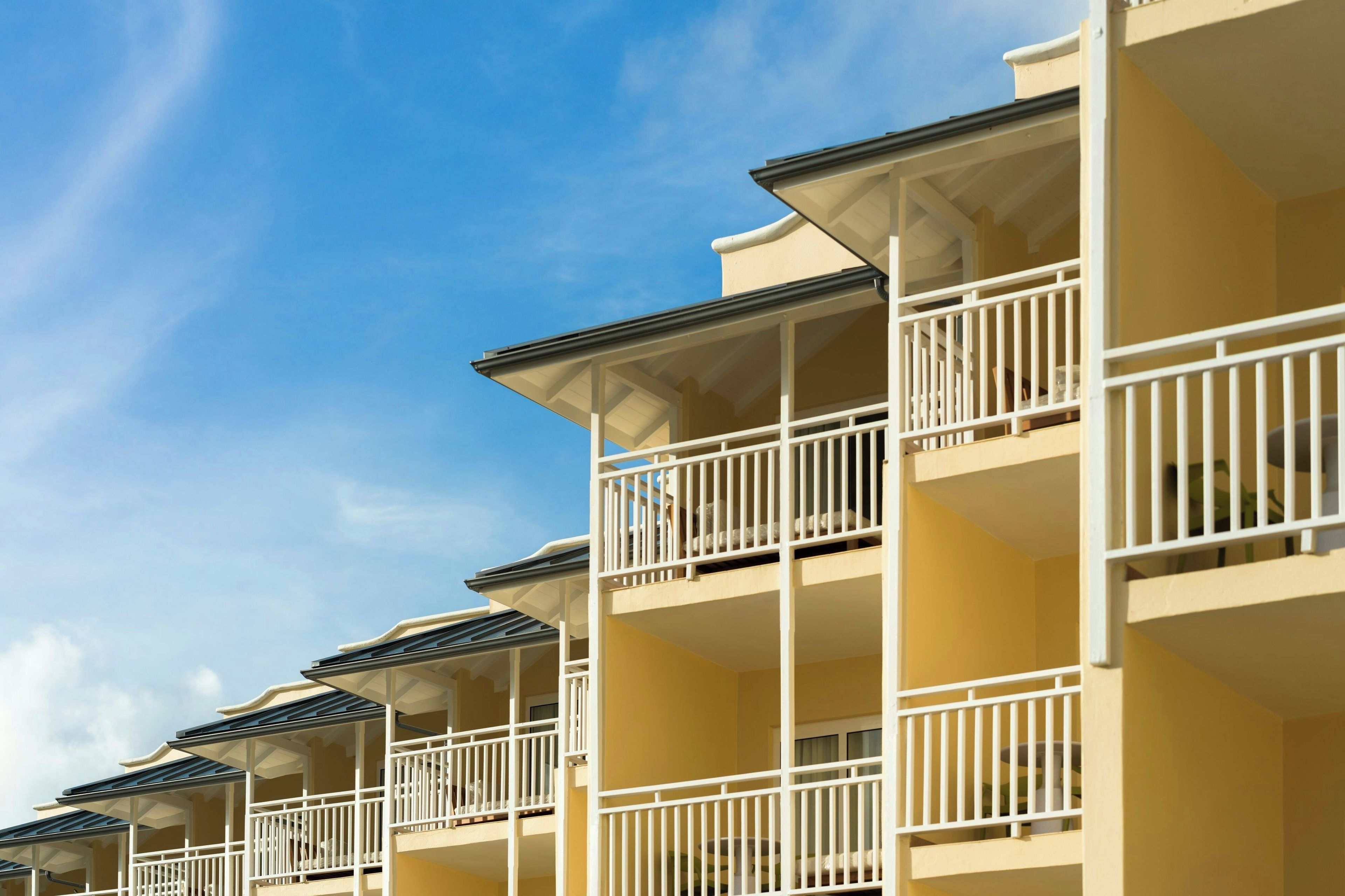 A hotel with multiple balconies, each with a white railing and a flat roof.