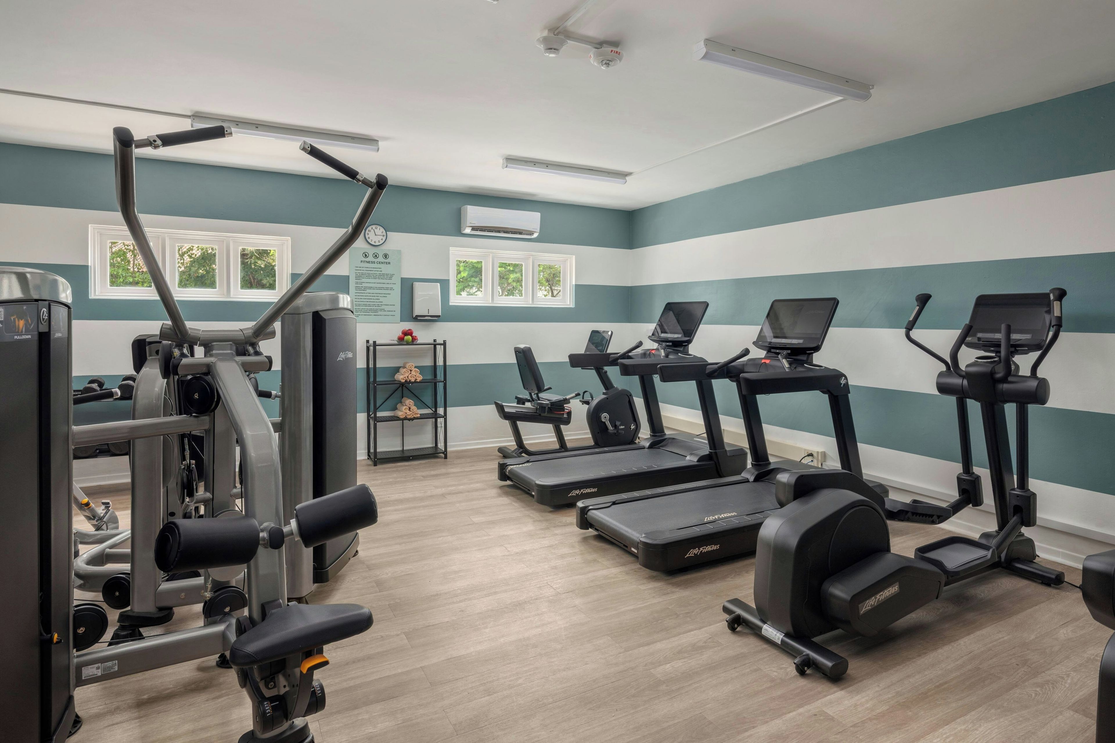 Un gimnasio con cintas de correr, elípticas y equipo de pesas.