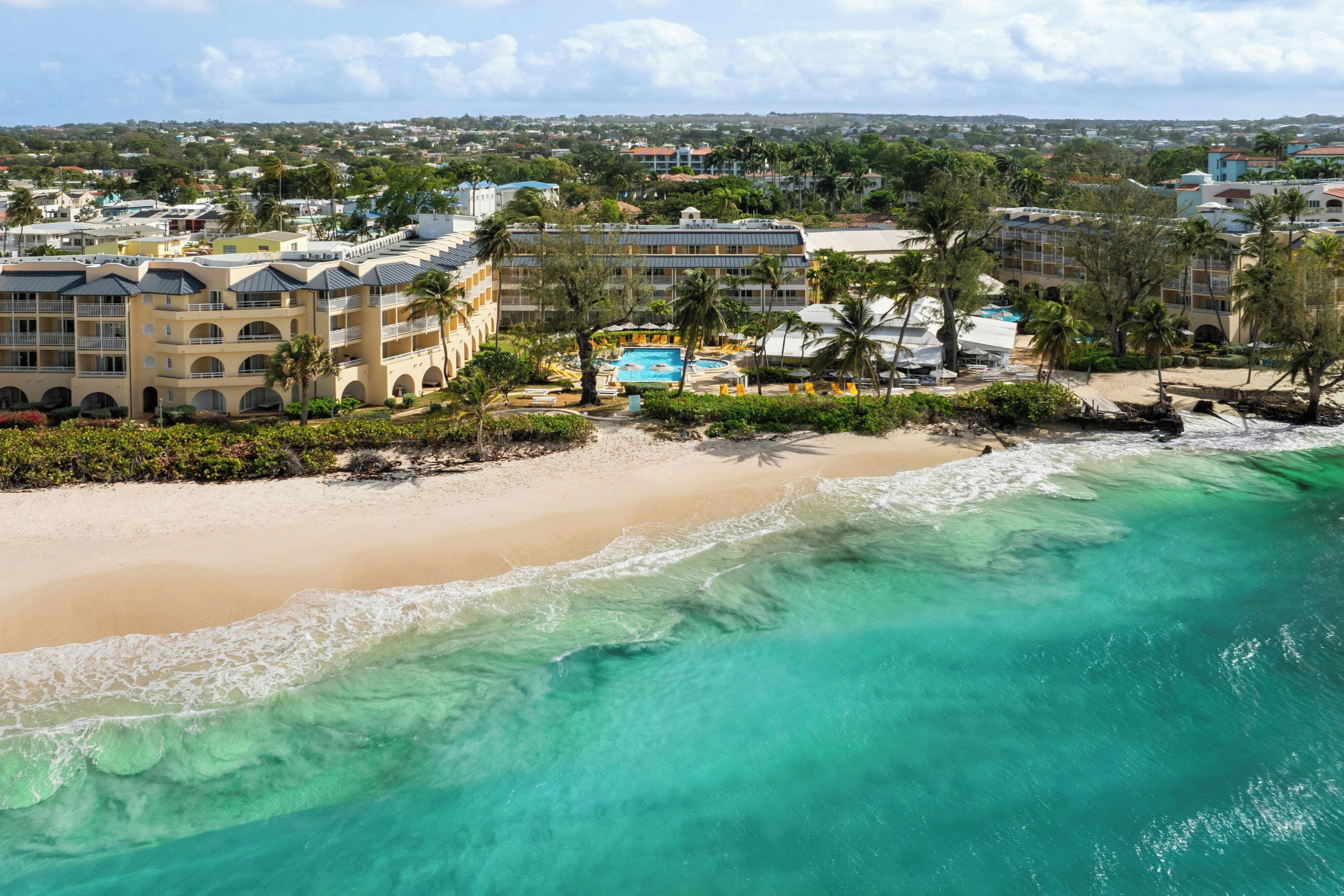 A beachfront hotel with multiple buildings, a swimming pool, and a beach.
