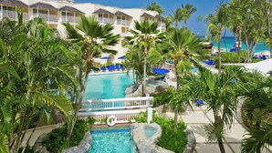 Un hotel con piscina, palmeras y vistas al océano.