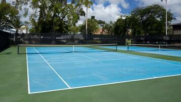A tennis court with a net in the center, surrounded by a green surface and a blue area.