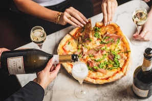 A group of people around a table with a pizza and wine glasses. - Novotel London Bridge (London)