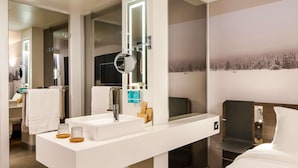 A modern bathroom with a large mirror, a white sink, and a vanity.