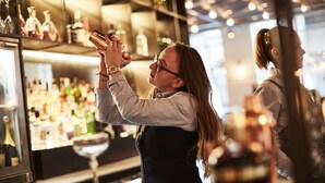 A bar setting with a bartender pouring a drink.