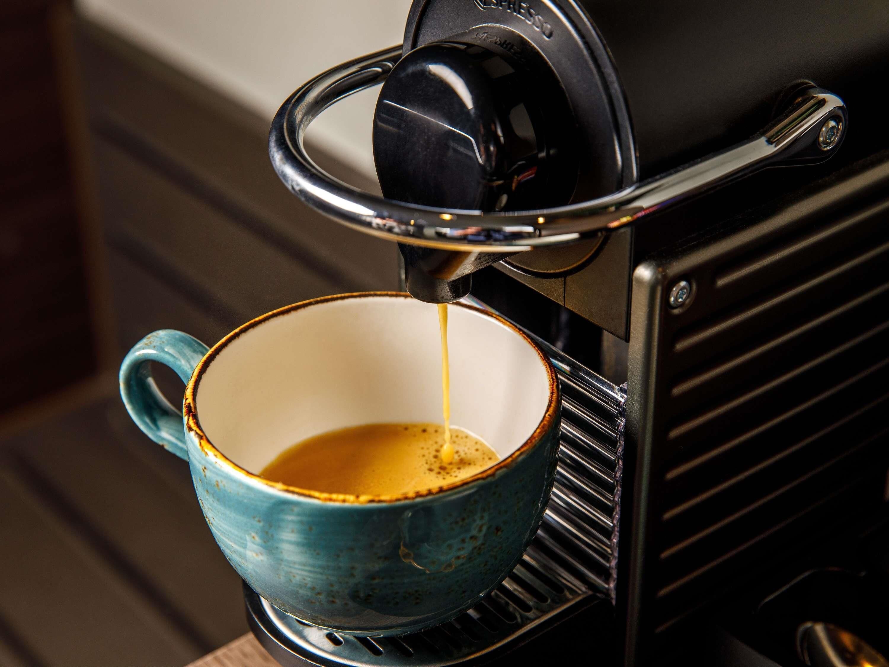 A coffee machine dispensing espresso into a ceramic cup.