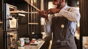 A person in a kitchen, preparing food with a pizza oven.