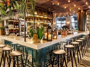 A bar area with a marble countertop, stools, and shelves stocked with bottles.