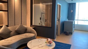 A modern living room with a curved sofa, a marble coffee table, and a large mirror. - Miracle Grand Convention Hotel (Bangkok)