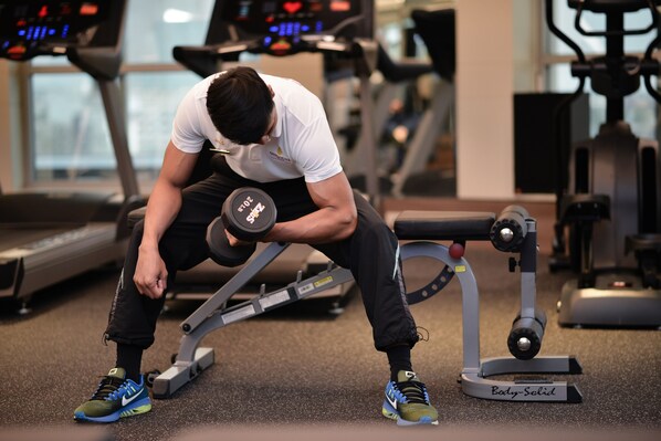 Un gimnasio con cintas de correr, una prensa de pesas y un banco para pesas.