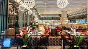 A restaurant with a long dining area, high ceilings, and hanging chandeliers. - Miracle Grand Convention Hotel (Bangkok)