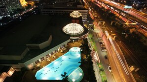 An aerial view of a hotel with a large swimming pool, a dome-shaped building, and a busy road with traffic lights. - Miracle Grand Convention Hotel (Bangkok)