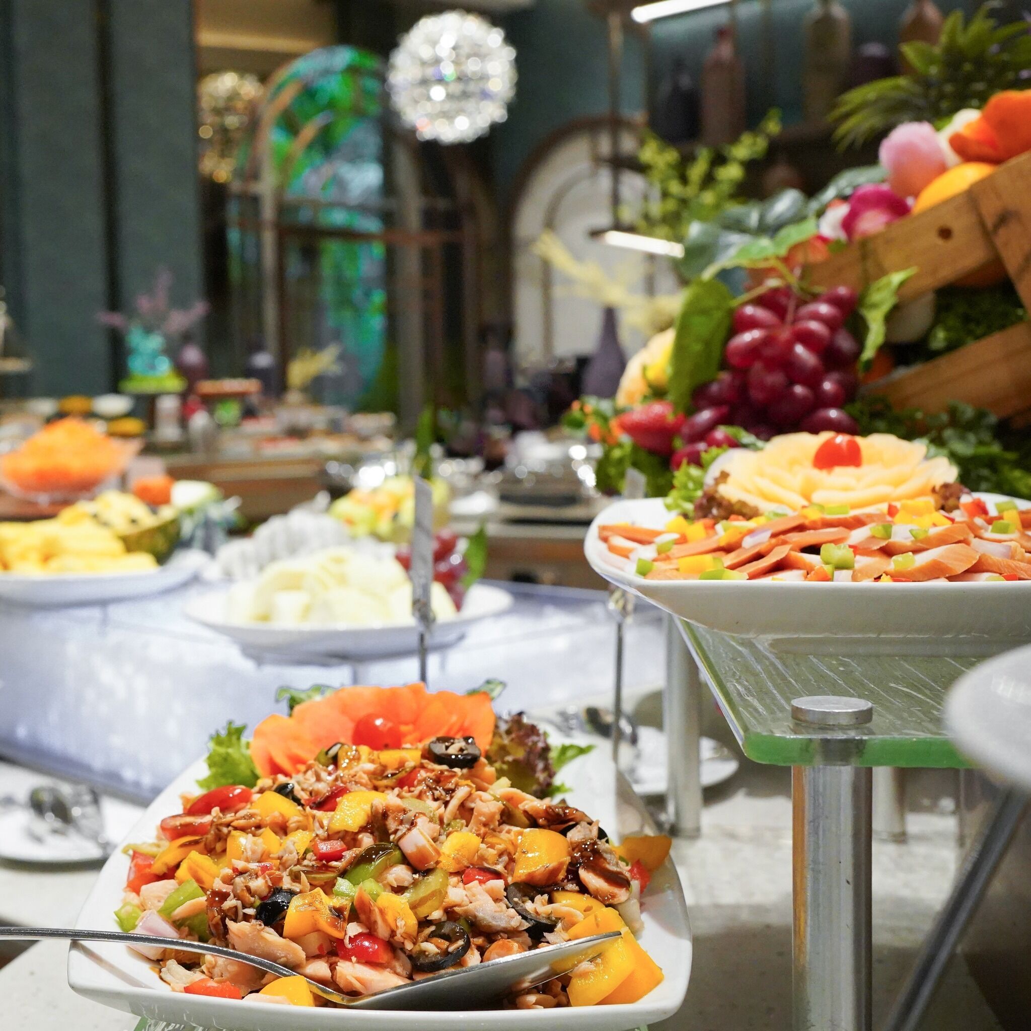 Ein Buffet mit verschiedenen Speisen, darunter ein Salat mit Meeresfrüchten, eine Obstplatte und eine Käseauswahl.