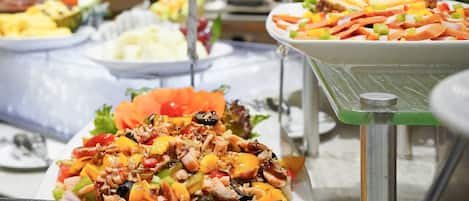 Ein Buffet mit verschiedenen Speisen, darunter ein Salat mit Meeresfrüchten, eine Obstplatte und eine Käseauswahl.