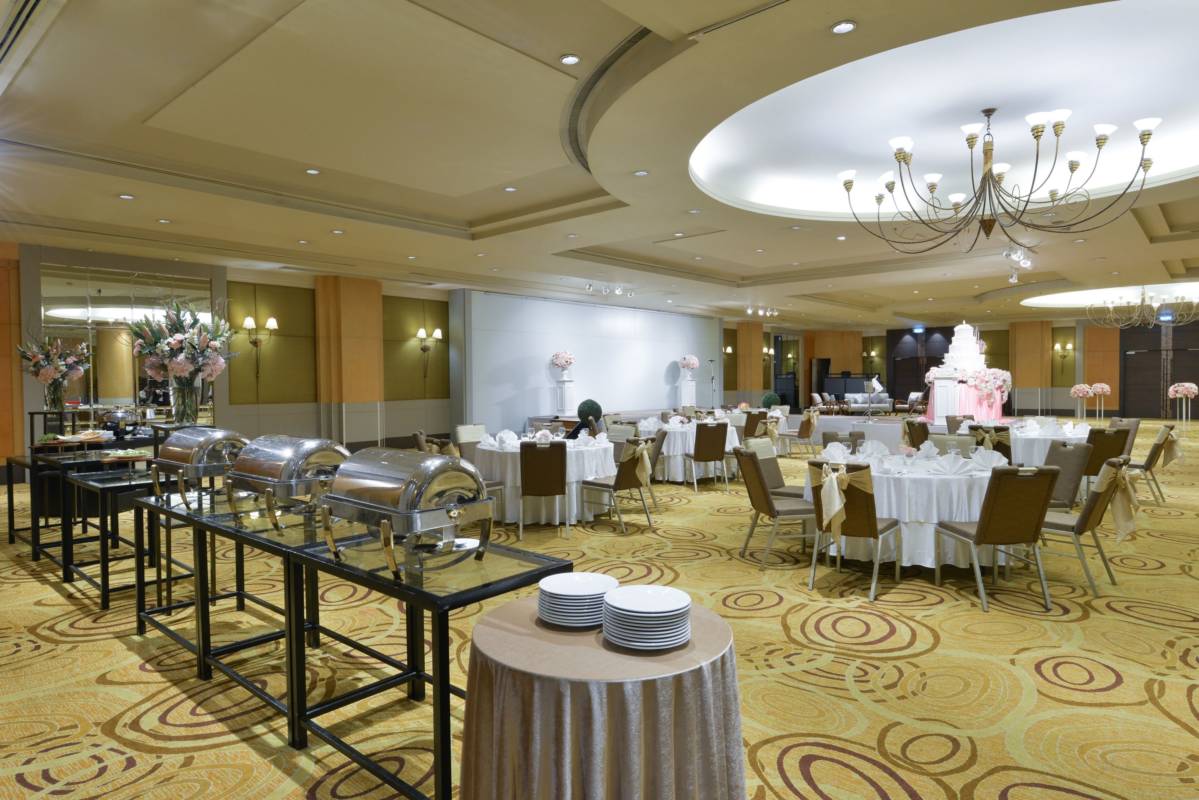 A banquet hall with round tables, chairs, and buffet stations.